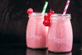 Front view of two jars with yogurt pink smoothie with cranberry, raspberry on black background.