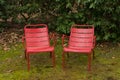 Front view of two red chairs inside a park.