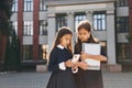 Front view. Two schoolgirls is outside together near school building Royalty Free Stock Photo