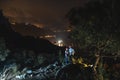 Front view. Two tourists on top of the mountain. Climbing, hiking trail. View of the night city. Romantic setting. Couple in love Royalty Free Stock Photo