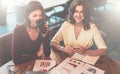 Front view. Two young cheerful businesswomen are sitting in cafe at table, drinking coffee and working together. Royalty Free Stock Photo