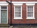 front view of a typical old english terraced brick house with yellow painted walls and maroon window and doors Royalty Free Stock Photo