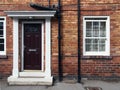 front view of a typical old small english terraced brick house with black painted door and white portico and windows Royalty Free Stock Photo
