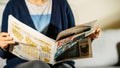 Front view of unrecognizable woman reading latest newspaper