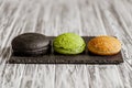 Front view of variety of three hamburger buns on wooden table. Black, green, yellow buns