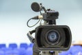 Front view of video camera with blurred hall background, selective focus. Royalty Free Stock Photo
