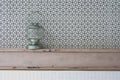 Front view of vintage kerosene oil lantern lamp setting on wooden shelf with black and grey geometric circle in the background.