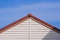 Front view of white artificial wooden gable roof with brown roof tile of vintage house against blue sky background Royalty Free Stock Photo