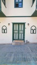 Front view of a white house with dark green door, windows and other elements