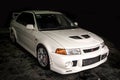 Front view of a white Mitsubishi Evolution VI in dark place.