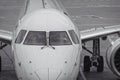 Front view of white modern jet airliner with close-up of cockpit windows. The plane is sitting on a concrete tarmac with Royalty Free Stock Photo