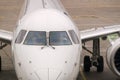 Front view of white modern jet airliner with close-up of cockpit windows. The plane is sitting on a concrete tarmac with Royalty Free Stock Photo