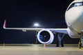 Front view of a white passenger airplane connected to an external power supply on an airport night apron Royalty Free Stock Photo