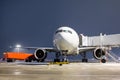 Front view of the white wide body passenger aircraft at the air bridge on night airport apron Royalty Free Stock Photo