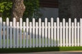 Front view of white wooden fence on artificial turf with sunlight and shadow on surface in front yard area Royalty Free Stock Photo