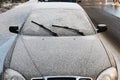 Front view of wipers and frosted car windshield covered with ice and snow, winter season