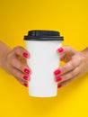 Front view woman holds big paper coffee cup isolated on yellow. White latte cup mockup with copy space