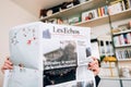 Front view of woman reading Les Echos French newspaper breaking