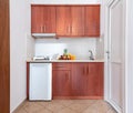 Front view of wooden kitchen cupboard module cabinet with small fridge and fruits plate. Classic style interior white studio room