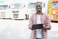 Front view. Young african truck driver is with his vehicle at daytime.