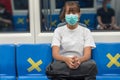 Front view of young Asian backpacker woman wear face mask sitting on the train seat, look at camera, travel to the city by subway Royalty Free Stock Photo