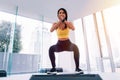 Front view of young attractive Asian fitness woman in sportswear doing deep squat at gym