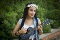 Front view of a young beautiful girl with braided hair, playing the ukulele Royalty Free Stock Photo