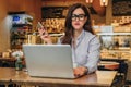 Front view. Young businesswoman is sitting in cafe working on laptop. Girl blogging, learning online, checking email. Royalty Free Stock Photo