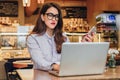 Front view. Young businesswoman is sitting in cafe working on laptop. Girl blogging, learning online, checking email. Royalty Free Stock Photo