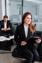 Front view of young businesswoman sitting using tablet in a modern office. Royalty Free Stock Photo