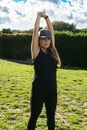 Front view of a young Caucasian woman in sportswear with arms outstretched in a park. Concept of outdoor pursuit in springtime and Royalty Free Stock Photo