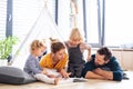 Young family with two small children indoors in bedroom reading a book. Royalty Free Stock Photo