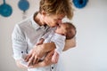 A young father holding a newborn baby at home, kissing.