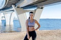 Front view of a young fitness woman under a bridge