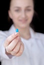 Front view of a young intellectual doctor on a black background with text space. The medical worker provider offers a pill Royalty Free Stock Photo