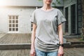 Front view. Young millennial woman dressed in gray t-shirt is stands on city street. Mock up. Royalty Free Stock Photo