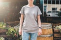 Front view. Young millennial woman dressed in gray t-shirt is stands on city street. Mock up. Royalty Free Stock Photo