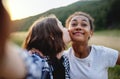 Front view of young teenager girls friends kissing outdoors in nature, taking selfie.