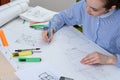 Front view of a young woman prepares architectural work at the table with a white drawing Board, ruler and pencil