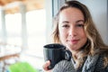 Young woman relaxing indoors at home with cup of coffee or tea. Royalty Free Stock Photo