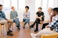 Front view of young woman telling about mental problem or addiction to other patients sitting in circle during group Royalty Free Stock Photo