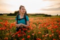 Front view of young woman tourist who stands on field of red poppies. Royalty Free Stock Photo