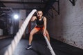 Young woman working out with battle ropes in cross fit gym Royalty Free Stock Photo