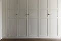 Front of a wardrobe with white wooden doors with golden metallic handles Royalty Free Stock Photo