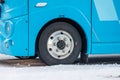 Front wheel of a blue electric bus..