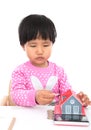 In front of the white background, the little girl is playing with the coins on the table and the model of the small house Royalty Free Stock Photo