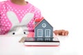 In front of the white background, the little girl is playing with the coins on the table and the model of the small house Royalty Free Stock Photo