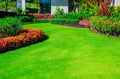 Front yard, landscape design With multicolored shrubs intersecting with bright green lawns Behind the house is a modern, garden ca Royalty Free Stock Photo