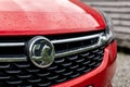 The frontal part of a red Vauxhall Astra hatchback car with a grill and badge of this auto maker