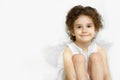 Portrait of adorable little girl with angelic face and smile in white dress and wings, isolated on white background. Royalty Free Stock Photo